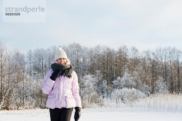 Mittlere erwachsene Frau in Winterkleidung im schneebedeckten Feld