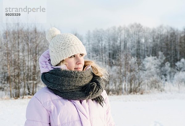 Mittlere erwachsene Frau in Winterkleidung im schneebedeckten Feld