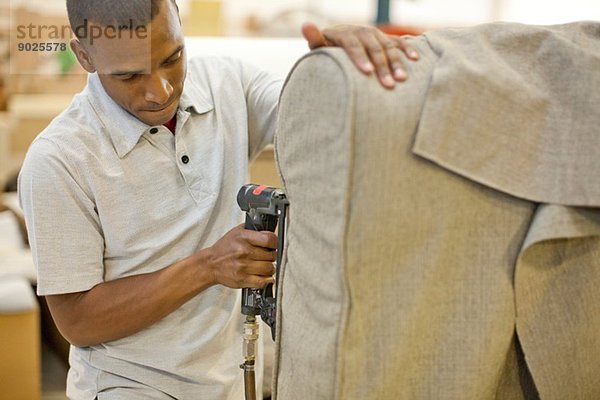 Polsterer zum Befestigen von Textilien auf dem Sofa mit einer Heftpistole