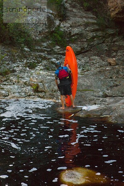 Mittlerer erwachsener Mann beim Kajakfahren an der Wasserseite