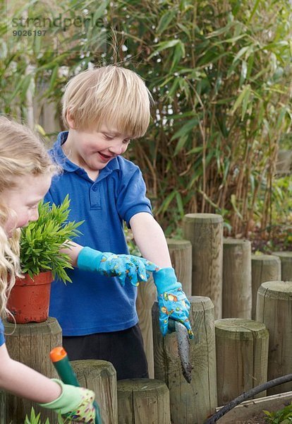 Schuljunge und -mädchen pflanzen im Garten