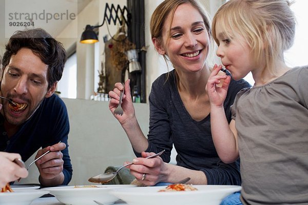 Mittlere erwachsene Eltern und zwei Töchter  die eine Spaghetti-Mahlzeit essen.