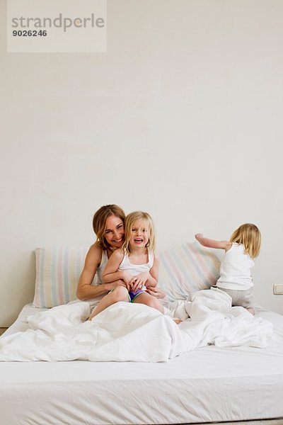 Porträt einer mittleren erwachsenen Frau im Bett mit zwei Töchtern