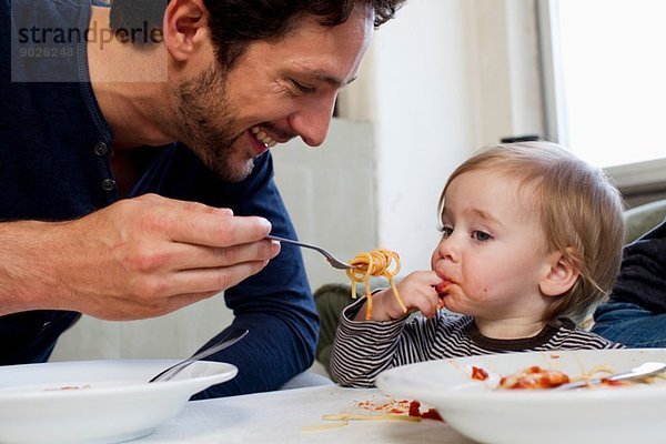Vater füttert eine einjährige Tochter Spaghetti