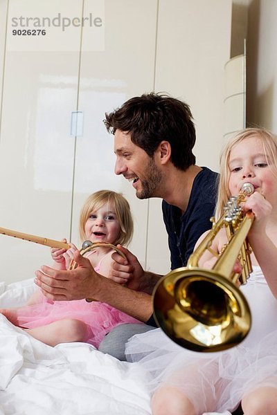 Vater und zwei junge Töchter beim Musizieren