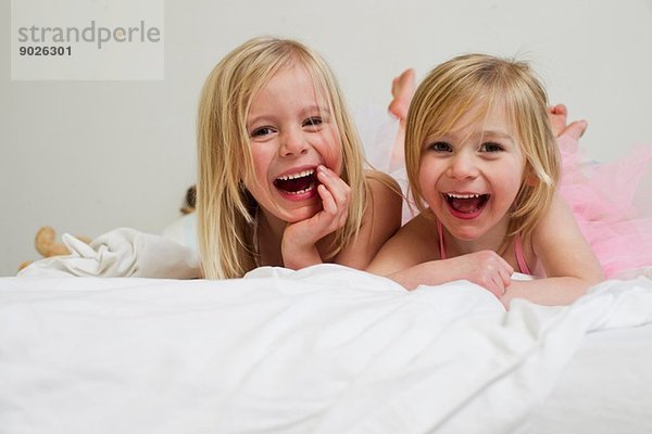 Porträt von zwei jungen Schwestern  die vorne im Bett liegen.