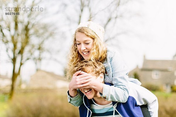 Teenagermädchen auf Huckepack  das die Augen von Teenagern bedeckt.