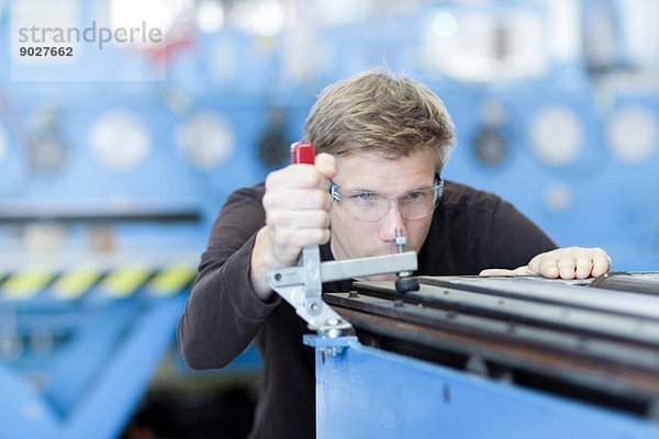 Mittlerer erwachsener Techniker  der die Messungen im Maschinenbaubetrieb überprüft.