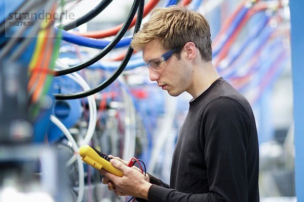 Mittlerer Erwachsener Techniker beim Testen von Kabeln im Maschinenbaubetrieb