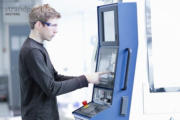 Mittlerer Erwachsener  männlicher Techniker  der Maschinen in einer Maschinenfabrik wartet.