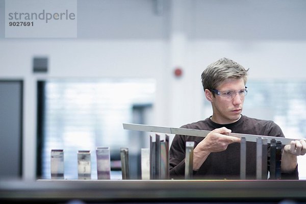 Mittlerer erwachsener Techniker  der die Qualität der Produkte im Maschinenbaubetrieb überprüft.