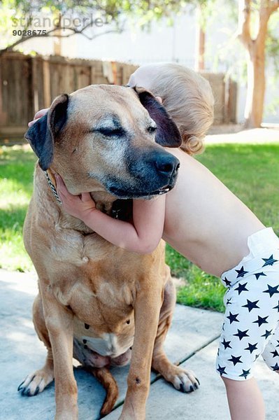 Weibliches Kleinkind umarmt alten Hund