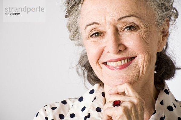 Porträt einer älteren Frau  Hand am Kinn  lächelnd