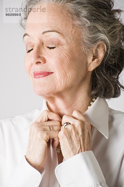 Porträt einer älteren Frau  Hände am Kragen  Augen geschlossen