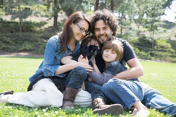 Porträt einer Familie mit zwei Jungen und einem Hund im Park