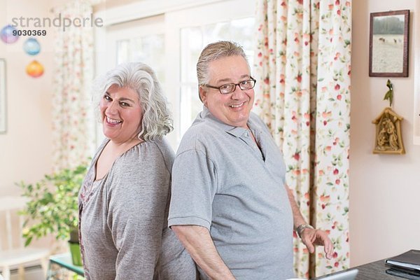 Porträt eines reifen Paares Rücken an Rücken im Wohnzimmer