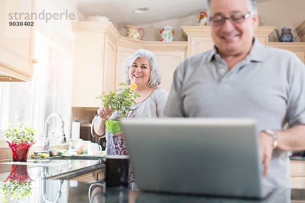 Reife Paare in der Küche mit Laptop