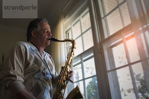 Erwachsener Mann zu Hause beim Saxophonspielen