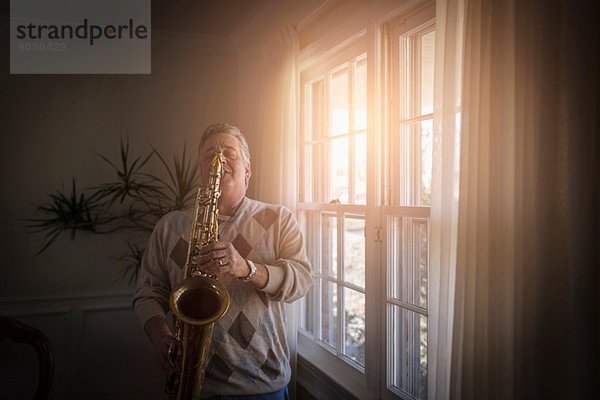 Erwachsener Mann zu Hause beim Saxophonspielen