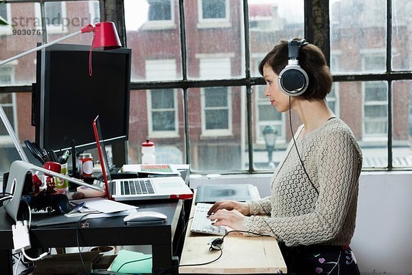 Junge Designerin mit Kopfhörer im Designstudio