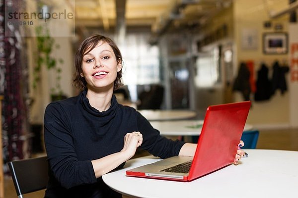 Portrait einer Designerin mit rotem Laptop