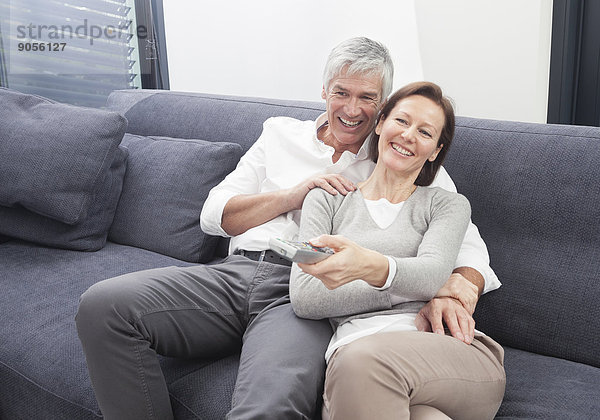 Paar sitzt auf der Couch und schaut in den Fernseher