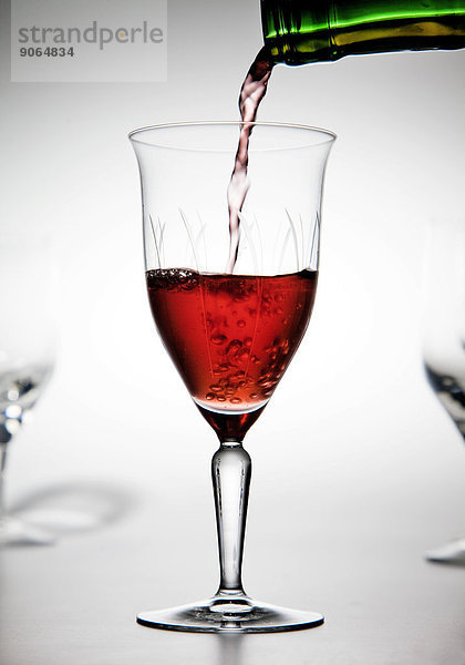 Rotwein wird in ein Weinglas gefüllt