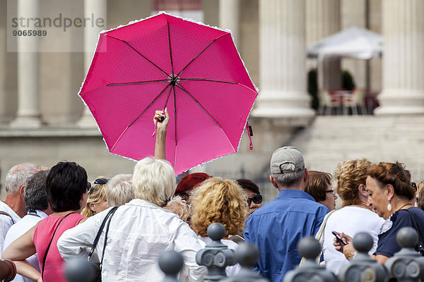Touristengruppe mit einer Touristenführerin mit pinkfarbenem Regenschirm  Budapest  Ungarn