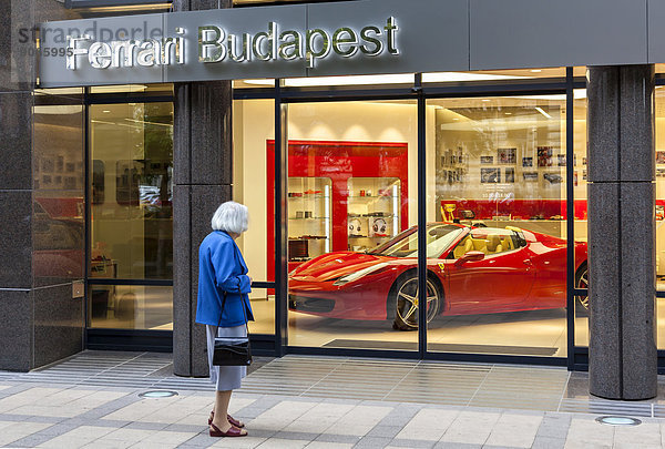 Eine alte Frau vor dem Schaufenster des Sportwagenherstellers Ferrari  Budapest  Ungarn