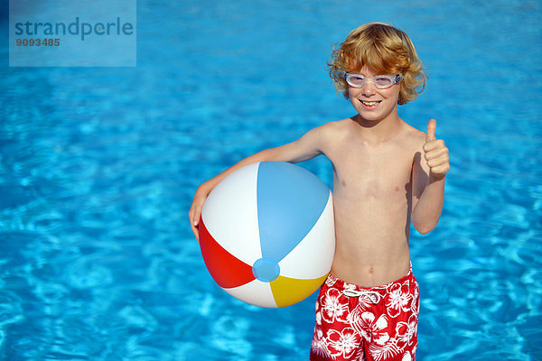 Ein Junge mit Schwimmbrille und buntem Wasserball im Freibad.