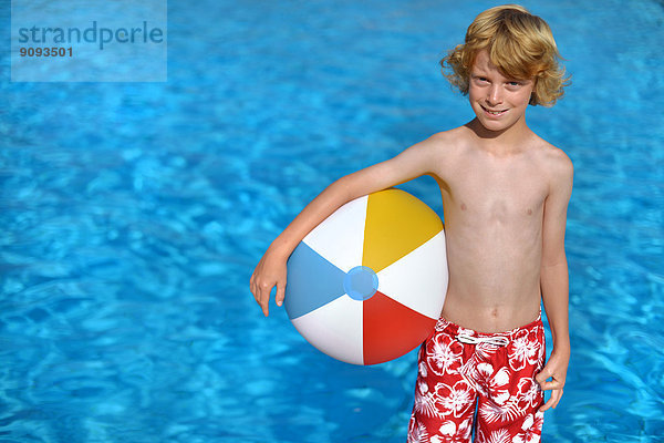 Ein Junge mit einem bunten Wasserball im Freibad