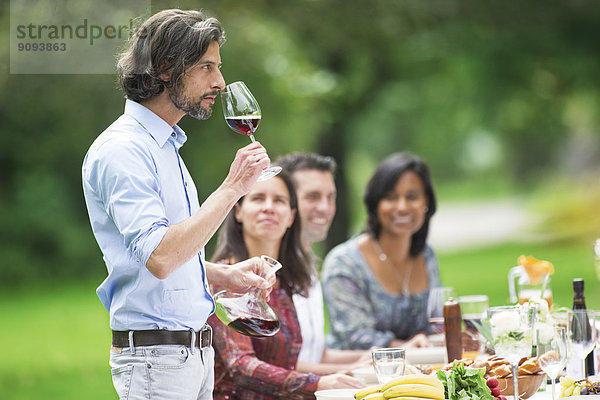 Mann probiert Rotwein auf einer Gartenparty