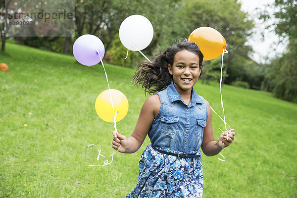 Lächelndes Mädchen mit Luftballons im Garten