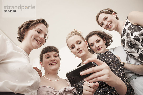 Junge Frauen in Vintage-Kleidern beim Blick aufs Handy