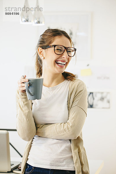 Porträt einer Frau mit Kaffeetasse im modernen Home Office