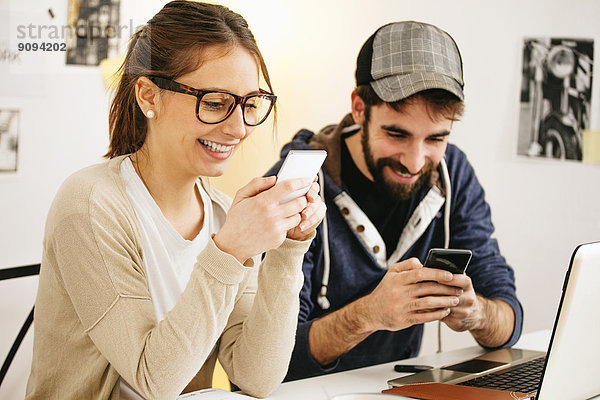 Junges Paar mit Smartphones im modernen Home Office