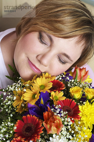 Deutschland  Mitterwachsene Frau hält Blumenstrauß  Augen geschlossen