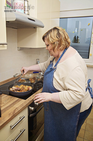 Deutschland  Mittlere erwachsene Frau in der Küche bei der Zubereitung von Speisen