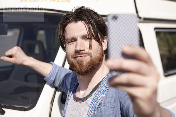 Mann  der Selfie vor dem Auto nimmt.