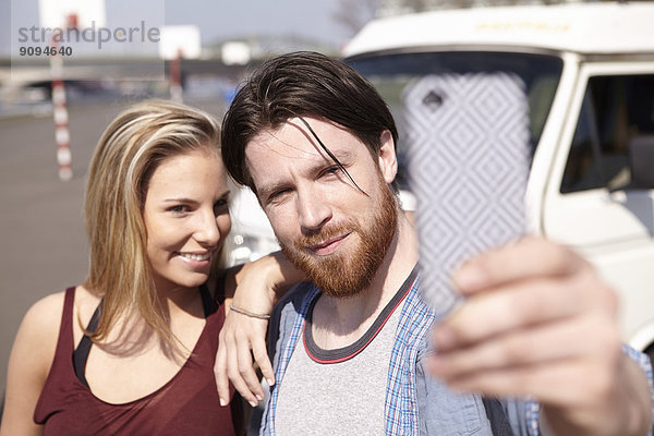 Mann nimmt Selfie mit Girlfiend vor dem Auto