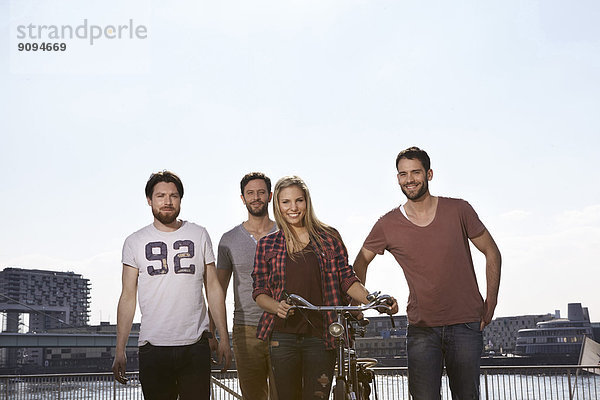 Vier lächelnde Freunde mit Fahrrad