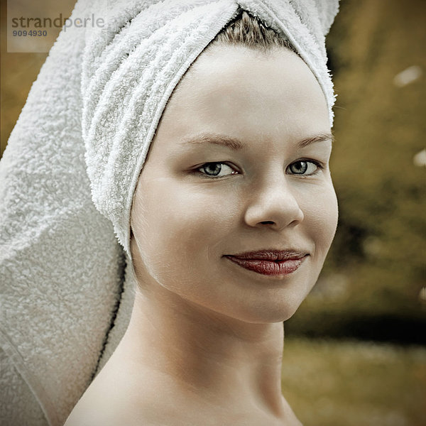 Porträt einer lächelnden Frau mit Handtuch auf dem Kopf