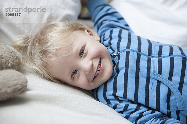 Porträt des lächelnden kleinen Jungen auf der Decke liegend