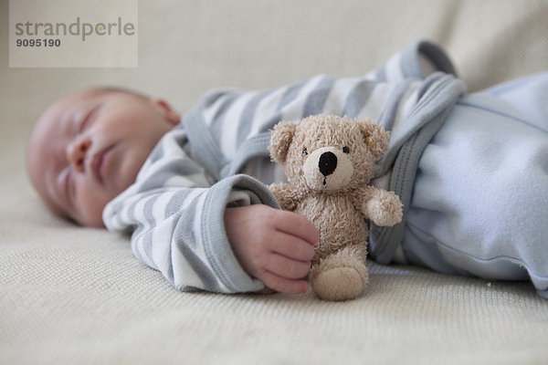 Porträt des schlafenden Jungen auf der Decke liegend mit Teddybär