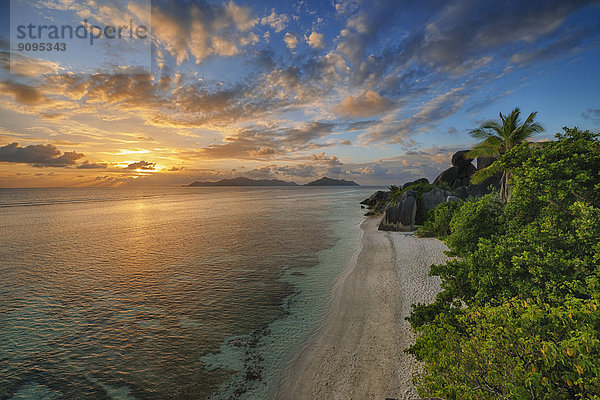 Seychellen  La Digue  Blick auf die Anse Source d' Argent mit skulptierten Felsen und Palmen bei Sonnenuntergang