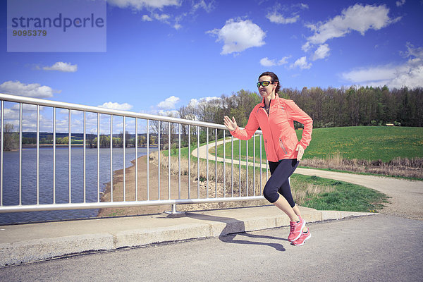 Frau joggt über eine Brücke