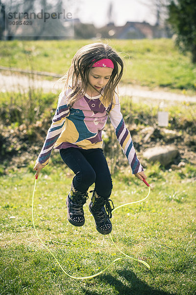 Kleines Mädchen springt Seil im Garten