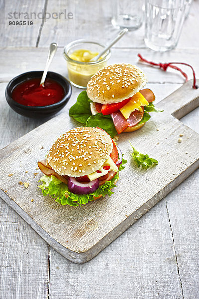 Zwei zubereitete Burger  Senf und Ketchup auf Holzboden