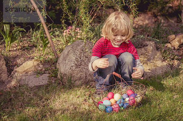Junge mit Osterkorb im Garten