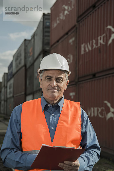 Mann mit Klemmbrett mit reflektierender Weste am Containerhafen